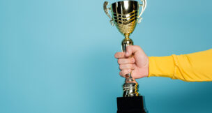 Cropped view of man holding golden trophy on blue. - DEPOSIT PHOTOS