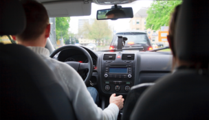 A person drives someone sitting in the backseat through traffic using a navigational device. Ridehailing drivers, like these, operate as unlicensed chauffeurs, not subject to the same regulations, the author argues. PHOTO: DEPOSIT PHOTOS
