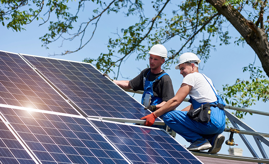Technicians mount heavy solar photo voltaic panel on tall steel platform